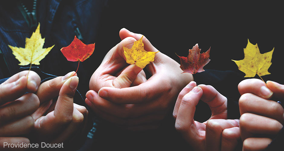 Symbolisches Motiv: Hände und Herbstblätter